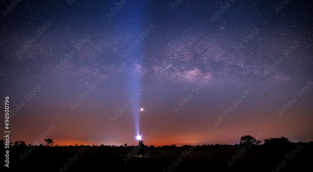 Wall mural silhouette tourist with flashlight in open field at night. space background with noise and grain. ni