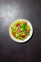 Linguini pasta with pesto sauce, tomatoes and cheese. Healthy eating. Vegetarian food. Italian cuisine.