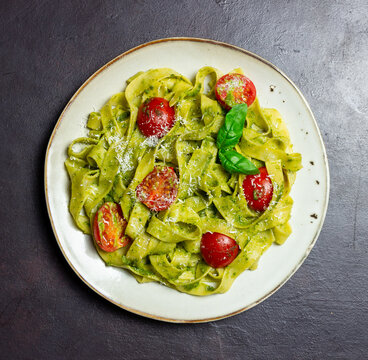 Linguini pasta with pesto sauce, tomatoes and cheese. Healthy eating. Vegetarian food. Italian cuisine.