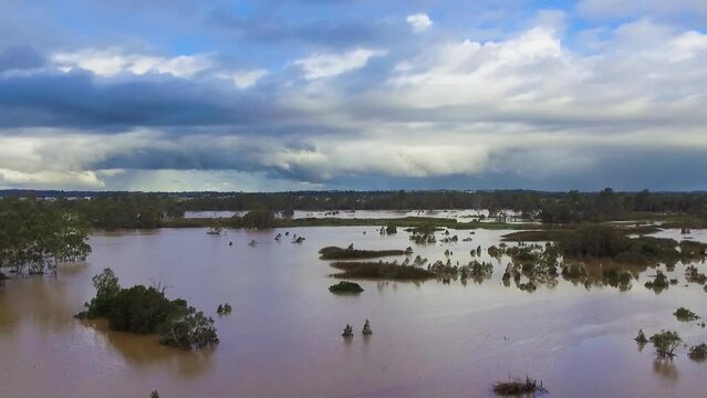 Queensland, NSW, Australia, February floods - dramatic aerial drone shot rising over inundated flood plains in Brisbane, under dramatic stromy skies