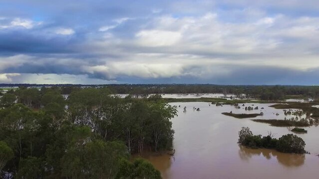 Queensland, NSW, Australia, February floods - dramatic aerial drone shot travelling over flooded bushland and over inundated flood plains in Brisbane, under dramatic stromy skies