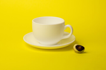 white cup with saucer and candy on a yellow background