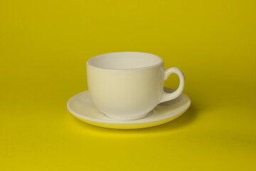white cup with saucer on a yellow background