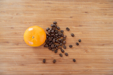 Grains de café et mandarine sur une planche en bois