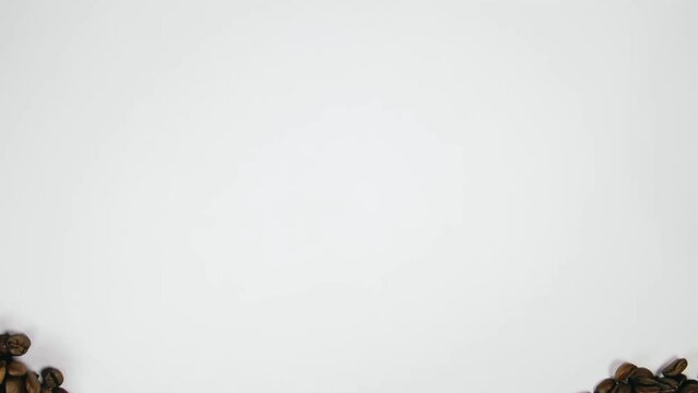 The coffee beans spin rotate quickly fast fly, dispart, splash to the sides with centrifugal coriolis force. The video is in reverse. Coffee beans twist, create pattern, make design figure picture.