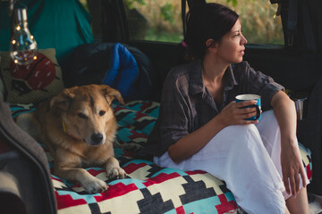 Happy Young Woman Sitting In Camper Van With Her Dog 