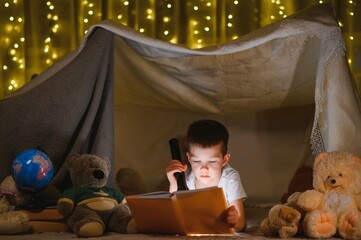the child is reading a book with a flashlight
