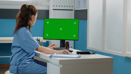 Woman working as nurse with green screen on computer. Healthcare specialist using monitor and...