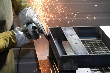 Almaty / Kazakhstan - 08.18.2020 : Grinding of metal products at the factory. A worker holds a tool in his hands.