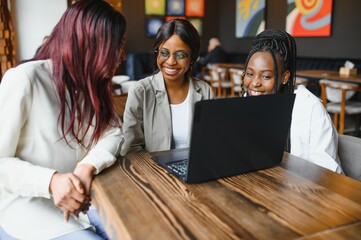 Technology is a fantastic resource for study tools. Three students at cafe.