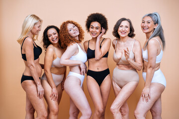 Beauty image of a group of women with different age, skin and body posing in studio for a body positive photoshooting. Mixed female models in lingerie on colored backgrounds