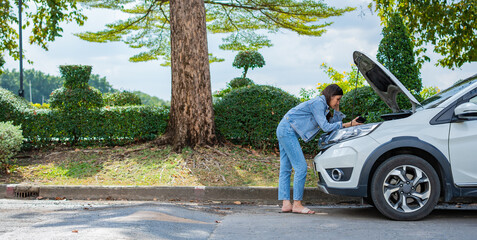 Angry Asian woman and using mobile phone calling for assistance after a car breakdown on street....