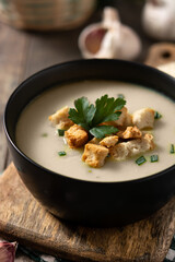 Garlic soup topped with croutons in bowl on wooden table	