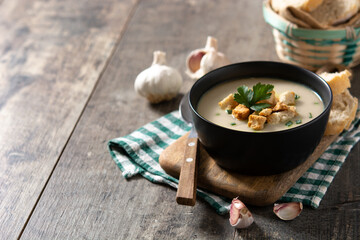 Garlic soup topped with croutons in bowl on wooden table. Copy space	