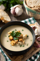 Garlic soup topped with croutons in bowl on wooden table	