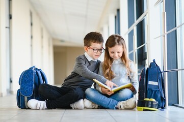 Portrait of smiling school kids in school corridor with books