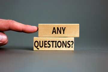 Any questions symbol. Concept words Any questions on wooden blocks on a beautiful grey table grey background. Businessman hand. Business and Any questions Q and A concept, copy space.