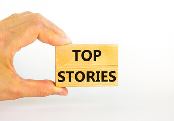 Top stories symbol. Concept words Top stories on wooden blocks on a beautiful white table white background. Businessman hand. Business story and top stories concept, copy space.