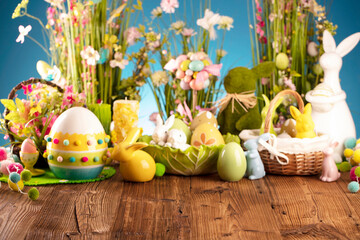 Fototapeta na wymiar Easter time. Easter decorations on the rustic wooden table. Easter bunny, easter eggs in basket and cabbage leaf. Bouquets of spring flowers. 