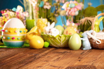 Obraz na płótnie Canvas Easter time. Easter decorations on the rustic wooden table. Easter bunny, easter eggs in basket and cabbage leaf. Bouquets of spring flowers. 
