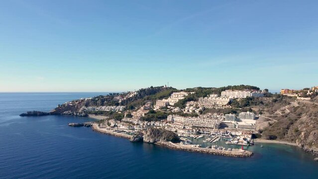 Aerial perspective of La Herradura city - Malaga Spain. Beautiful coastal city situated in south of Spain. View of the port and luxury urbanisation on hills. Mountains in background. Dolly forward