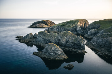 In the picturesque rocky bay of Belle-ile en Mer, large rocks lie in the calm waters in a tranquil...