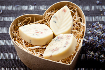 Handmade leaf shape bath truffles, buttery version of the bath bomb in heart shape cardboard on black background. Home spa concept.