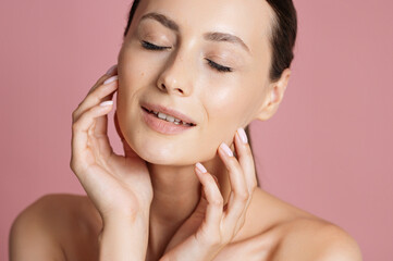 Tender woman with shiny skin posing over pink background