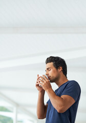 Savoring the aroma of a freshly ground cup of coffee. Profile of a handsome young man holding a cup...