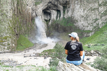 Obraz premium A girl on the background of the Tuzluk-Shapa waterfall on the territory of Kabardino-Balkaria. Caucasus. Russia.