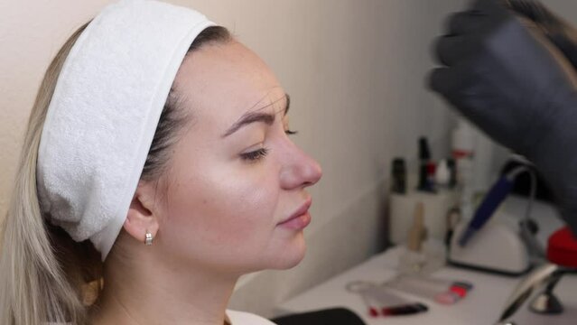 Eyebrow tattooing .Permanent eyebrow makeup master applies the contour with thread on the client's eyebrow