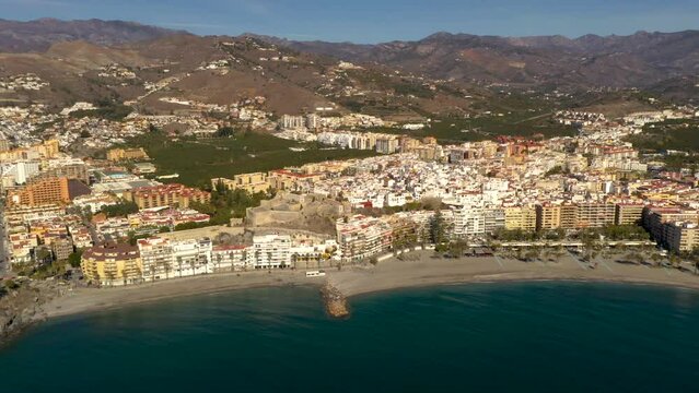 Drone truck left creating a beautiful aerial perspective of Spanish city Almu&ntilde;ecar, province of Granada. In background beautiful Sierra Nevada mountains.