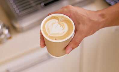 Making my coffee extra special for myself. Shot of an unrecognizable man holding a cup of coffee with coffee art.