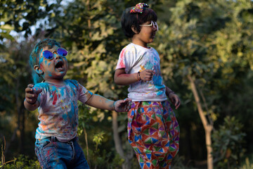 Happy Asian Indian Kids Boy And Girl Enjoying The Festival Of Colors With Holi Color Powder Called Gulal Or Rang