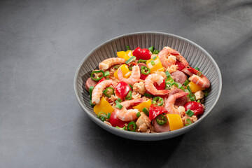 Jambalaya rice with chicken, shrimp, sausage and vegetables in plate on dark table