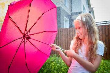 Pity blonde child with pink umbrella under the summer rain with su. Girl enjoying rainfall. Kid playing on the nature outdoors