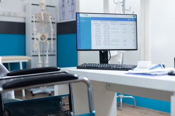 Empty hospital examination office equipped with medical professional tools ready for disease consultation. Computer with patient diagnosis on screen standing on table. Health care support services