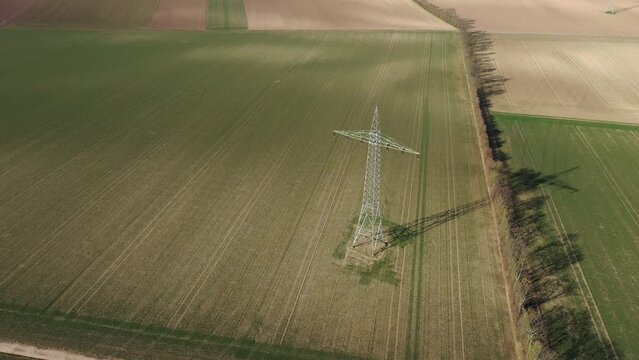 Luftaufnahme Video in 4K von einem Strommasten und Windkraftanlagen auf &Auml;ckern und Feldern in Deutschland