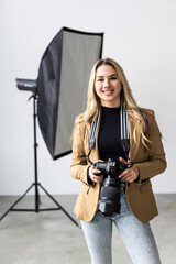 Young beautiful female posing for a photo shoot in a studio, a photographer is shooting with a digital camera
