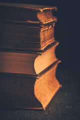 Stack of antique leather bound books against dark background