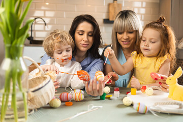 Mothers with children coloring eggs for the Easter holidays
