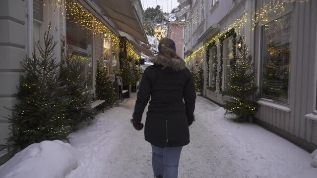 Woman Walking Around Kragero Winter Town, Shops Illuminated With Christmas Lights Decorations - wide shot