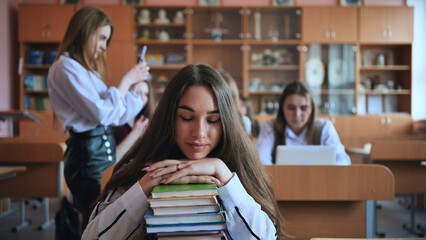 A student poses with textbooks at her desk in her class.