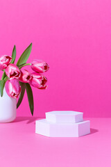 Pink podium for product display on pink with tulips flowers in hard light
