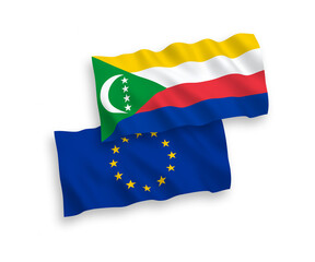 National vector fabric wave flags of European Union and Union of the Comoros isolated on white background. 1 to 2 proportion.