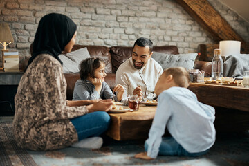 Happy Muslim man talks to his family while having dessert together at home. - obrazy, fototapety, plakaty