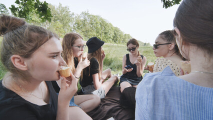 Girlfriends eat ice cream at a picnic outside the city.