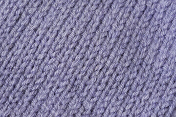 Knitted texture background. Hand-knitted wool. Macrophotography of a thread drawing. Gray-lilac texture of sweaters, pullovers, cardigans. Abstract natural background. Comfort autumn warmth concept
