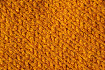 Knitted texture background. Hand-knitted wool. Macrophotography of a thread drawing. Orange bright texture of sweaters, pullovers, cardigans. Abstract natural background. Comfort autumn warmth concept