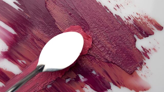 Texture of lipstick samples close up. Spatula and red paint. Advertising of decorative cosmetics. Advertising concept. Move the spatula over the red texture. Red color.
